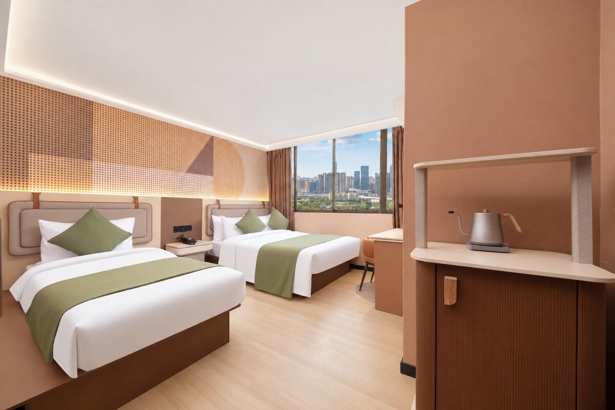 Habitación de hotel con dos camas, un escritorio, vista a la ciudad y diseño moderno.