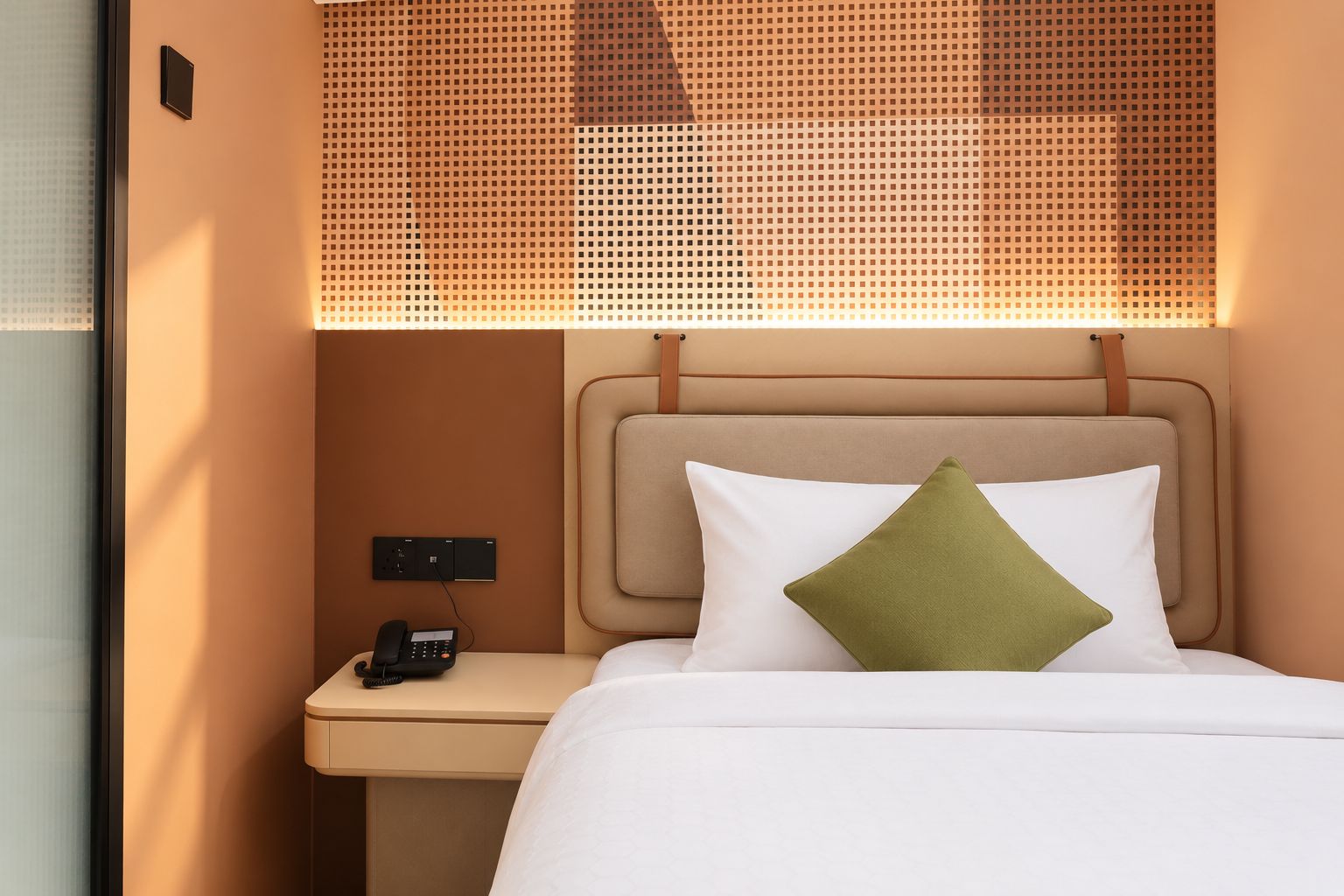 Une chambre d’hôtel avec un lit, une table de chevet avec un téléphone et un interrupteur fixé au mur.