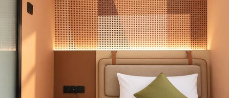 Une chambre d’hôtel avec un lit, une table de chevet avec un téléphone et un interrupteur fixé au mur.