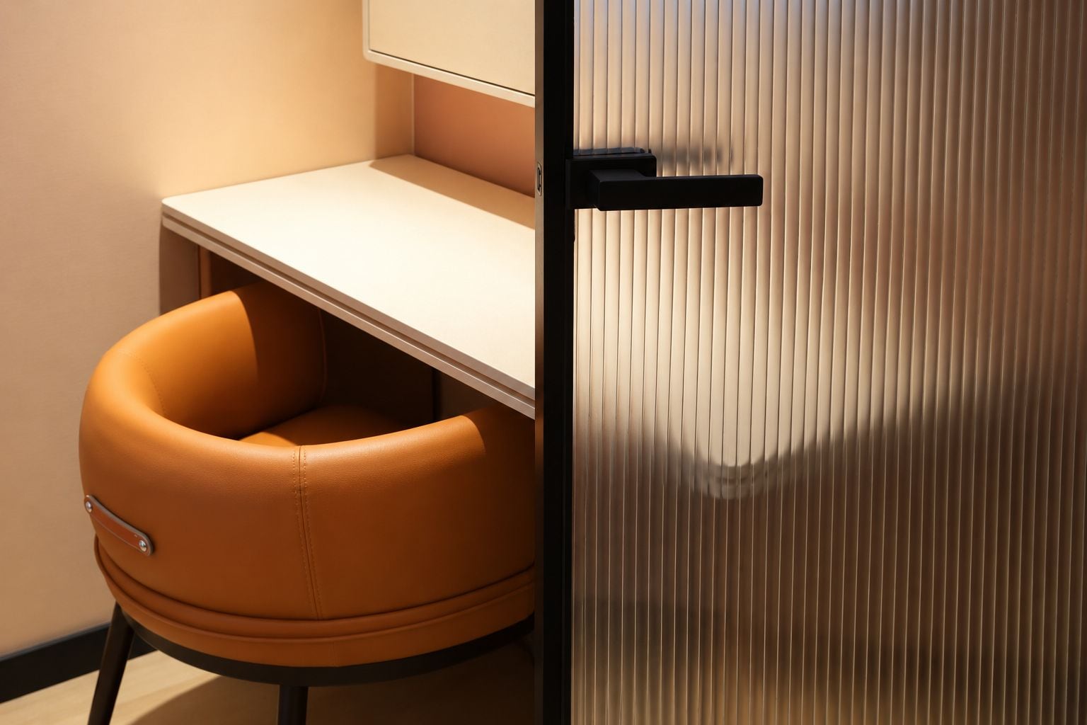 A corner office with a desk, a chair, and a door.