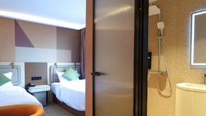 Habitación de hotel con dos camas, baño con ducha y una pequeña mesa con teléfono.