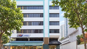 Un edificio de varios pisos con un toldo verde que dice 'A HOTEL FARRER PARK' y un letrero que anuncia 'BIG CITY COFFEE HOUSE' en la planta baja.