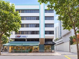 Un edificio de varios pisos con un toldo verde que dice 'A HOTEL FARRER PARK' y un letrero que anuncia 'BIG CITY COFFEE HOUSE' en la planta baja.