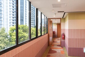 Un pasillo con ventanas amplias, un extintor y vistas de un paisaje urbano.