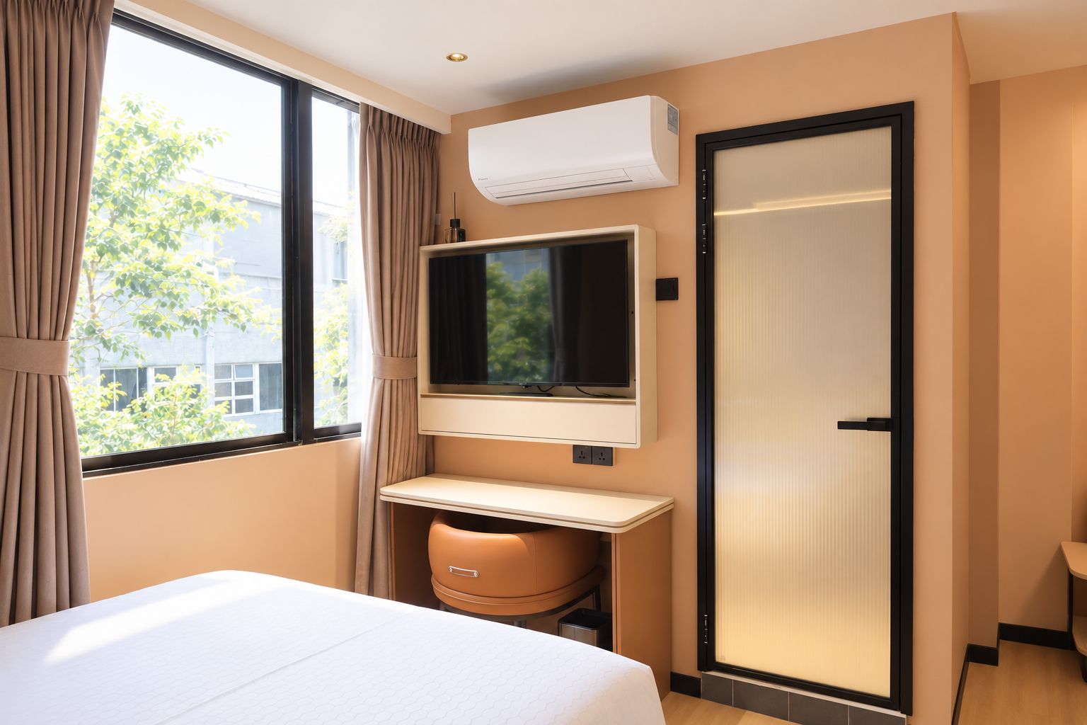 Una habitación de hotel con cama, televisor montado en la pared, ventana con cortinas y aire acondicionado.