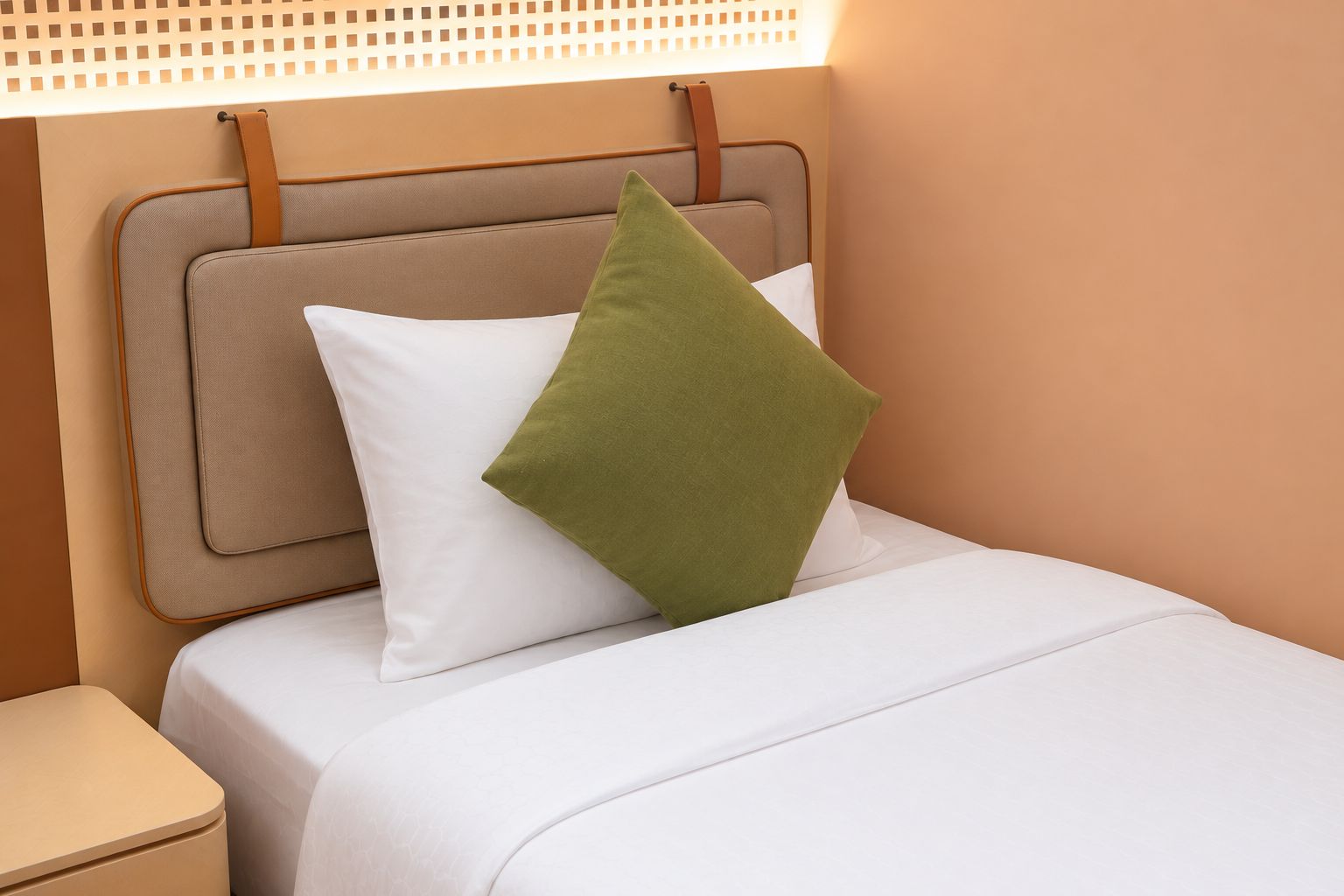 Una cama con cabecera, almohada y mesita de noche.