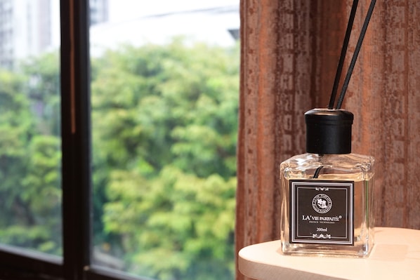 A bottle of La Vie Parfaite perfume on a wooden surface near a window with a view of trees. - A Hotel Farrer Park - Newly Renovated (Singapore)