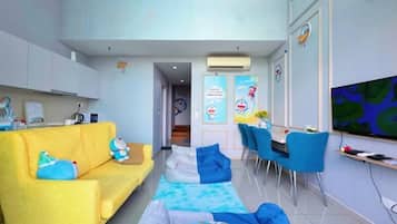 A modern living room with a yellow sofa, blue chairs, and a flat-screen TV.