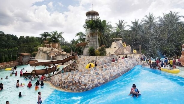 Un parque acuático con una piscina grande, toboganes y una estructura tipo torre.