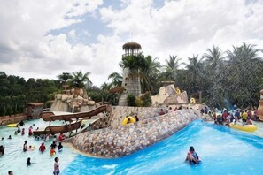 Een waterpark met een groot zwembad, glijbanen en een torenstructuur.