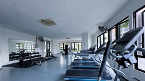 Un gimnasio con cintas de correr, mancuernas y equipo de ejercicio.