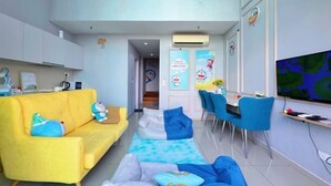 Una sala de estar moderna con un sofá amarillo, un sillón de peluche azul y un comedor con sillas azules.