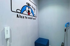 A bathroom with a cartoon character wall decal, a blue bench, and a hand dryer. - Doraemon @ Hyde Towel Duplex Fully AiCON 2BR (Shah Alam)