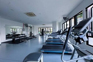 Une salle de sport équipée de tapis de course, de poids et d'appareils d'exercice.