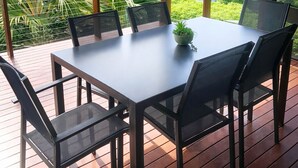 Un comedor con mesa y sillas, ventilador de techo y vistas a un paisaje exuberante.