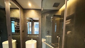 A modern bathroom with a glass-enclosed shower, a large mirror, and a round sink. - 1BR with Rooftop Pool & Gym  C191 (Kamala)