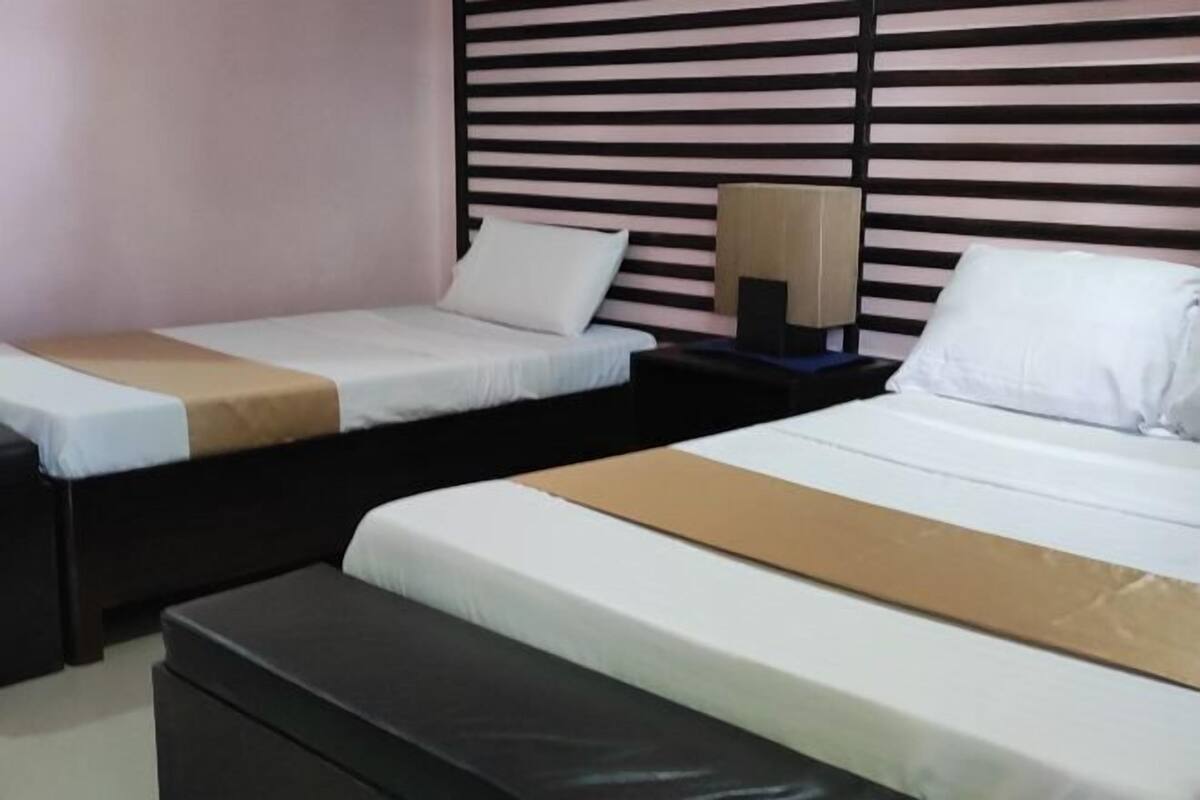 Ein Hotelzimmer mit zwei Betten, einem Nachttisch und einer Wand mit horizontalen Lamellen.