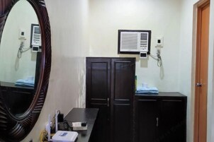 Un baño con un espejo grande, un mueble negro, una encimera blanca y un aire acondicionado instalado en la pared.