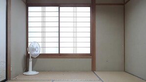A room with tatami flooring, a shoji screen, and a standing fan. - Fuse Hot Spring Stay East (Saku)