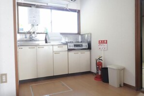 A kitchen with white cabinets, a gas stove, and a window. - Fuse Hot Spring Stay East (Saku)