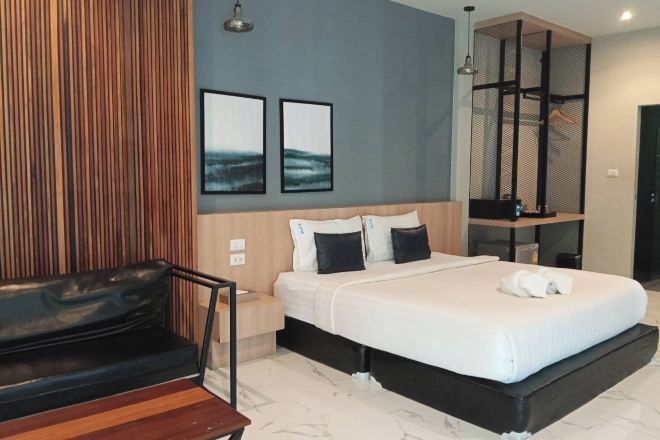 Una habitación de hotel moderna con una cama, un banco de madera y una pequeña mesa.