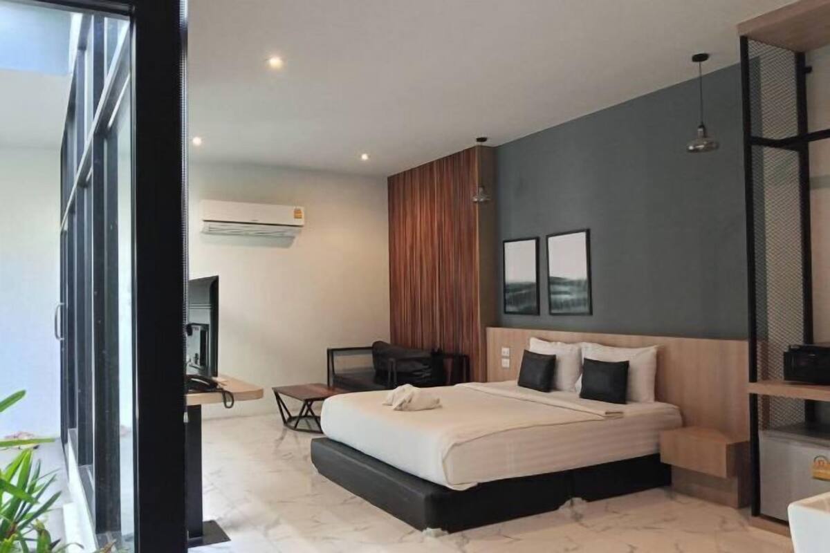 A modern hotel room with a large bed, a desk, and a seating area.