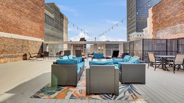 An outdoor patio with wicker furniture and a patterned rug. - Cozy 1-bedroom loft ~ Playhouse Square ~ Fitness, BBQ, Fire pit, business center (Cleveland)