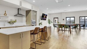 A modern kitchen with a white countertop, stainless steel appliances, and a large island with bar stools. - Cozy 1-bedroom loft ~ Playhouse Square ~ Fitness, BBQ, Fire pit, business center (Cleveland)