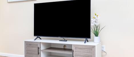 Un mueble de entretenimiento moderno con un televisor de pantalla plana, armarios de madera y una planta en maceta.