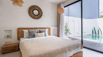 Un dormitorio con una cama grande, un espejo redondo y vistas a una piscina.