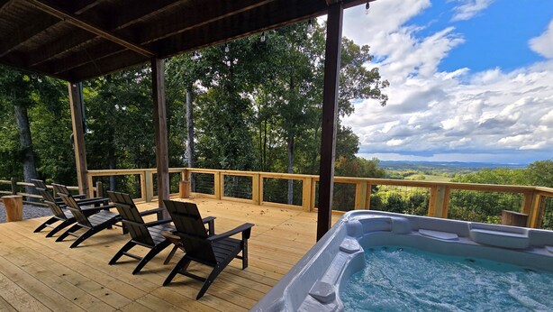 Um deck de madeira com hidromassagem e cadeiras de descanso com vista para uma paisagem deslumbrante.