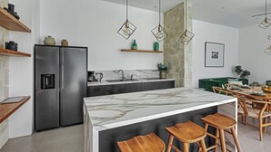 A modern kitchen with a central island, stainless steel appliances, wooden bar stools, and pendant lighting. - New Magnificent 3BR 5min to Finns & Berawa Beach Villa Alemar (Bali)