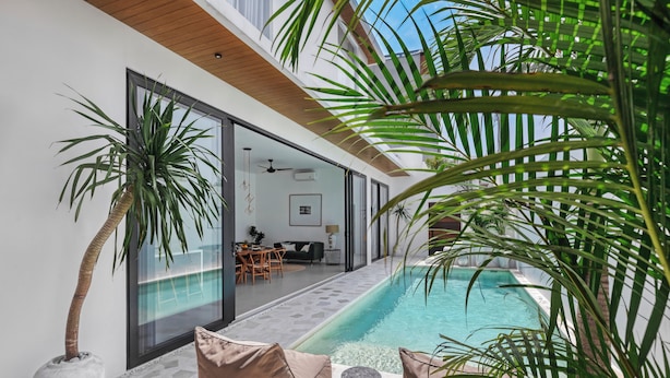 A modern outdoor pool area with a glass-enclosed patio, lounge chairs, and a dining area. - New Magnificent 3BR 5min to Finns & Berawa Beach Villa Alemar (Bali)