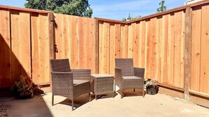 A wooden fence with two wicker chairs and a small table. - Remodeled Spanish Bungalow Suite • Short Walk to SJSU + Parking (San Jose)