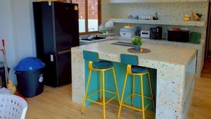 Eine kompakte Küche mit einem schwarzen Kühlschrank, einer Spüle und einer Bartheke mit Hockern.