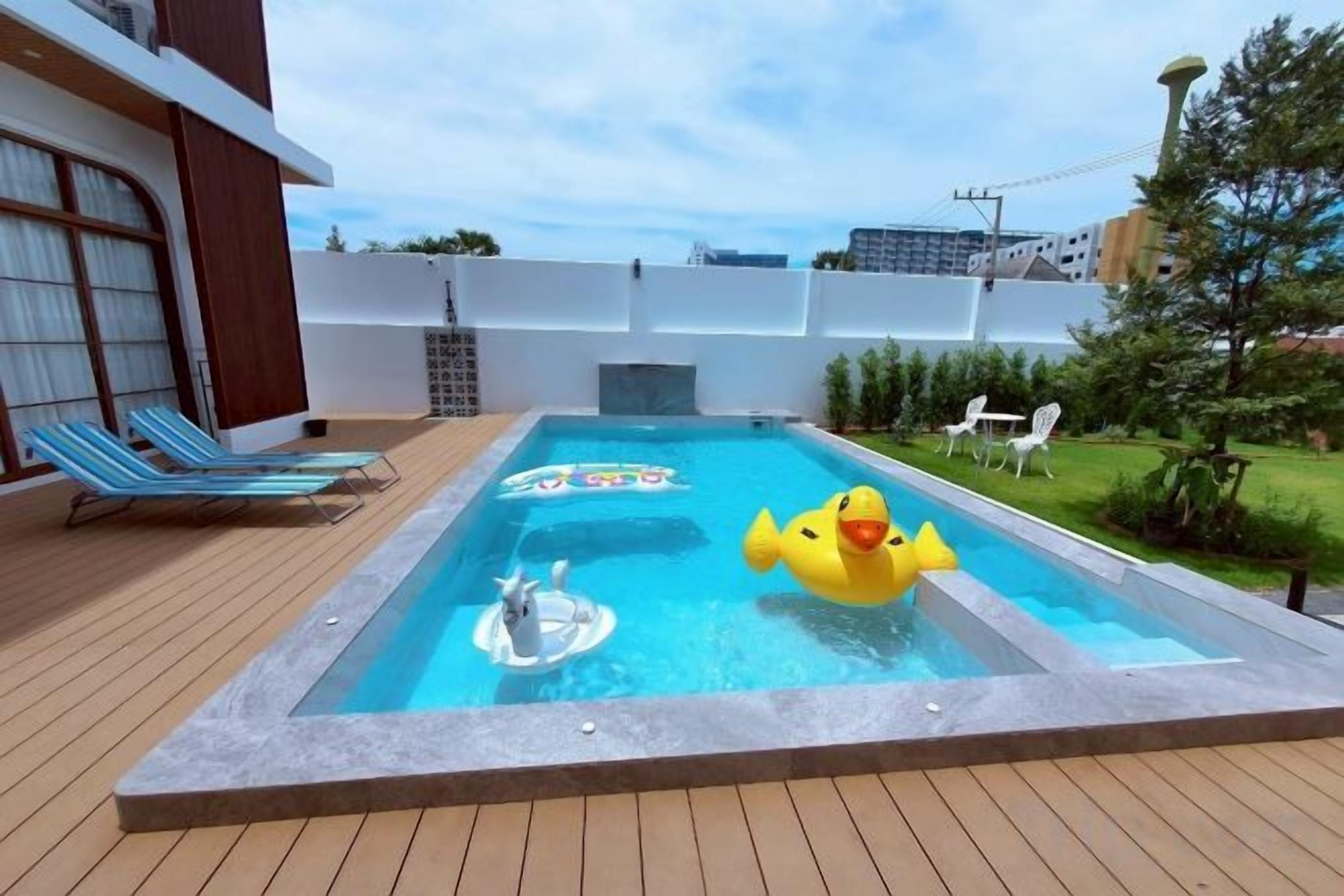 A pool area with a hot tub, lounge chairs, and a yellow inflatable duck.