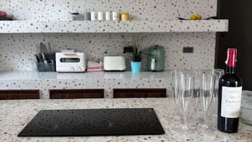 A kitchen counter with a wine bottle, glasses, a toaster, and a plant.