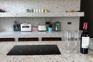 A kitchen counter with a wine bottle, glasses, a toaster, and a plant. - Villa NaRa Chaam (Cha-am)