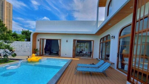Ein moderner Poolbereich mit Holzterrasse, Liegestühlen und einem Pool voller Luftmatratzen.