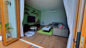 Ein modernes Wohnzimmer mit einer Couch, einem Couchtisch, einem Fernseher und einem Bücherregal.