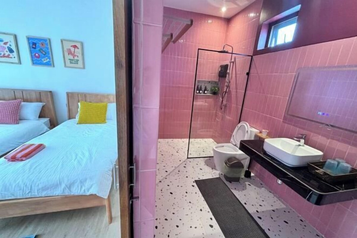 A bedroom with a bed, bedside tables, and a bathroom with a shower, toilet, and sink.
