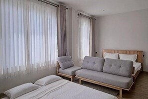 Un dormitorio con cama, dos sofás y una ventana con cortinas.
