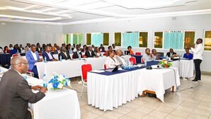 A conference room with round tables, chairs, and attendees. - ALLENS HOTEL (Kapsabet)