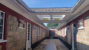 A corridor with stone walls, tiled flooring, and a covered walkway. - ALLENS HOTEL (Kapsabet)
