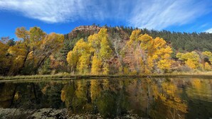 A calm lake reflecting autumn trees and a rocky hill in the background. - Yun-Shui Garden 
Where Clouds Drift, Water Flows (Durango)