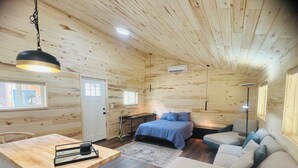 A cozy cabin interior with a wooden interior, a bed, a sofa, a dining area, and a small kitchen. - Yun-Shui Garden 
Where Clouds Drift, Water Flows (Durango)