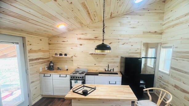 A compact kitchen with wooden walls, a central island, and a built-in stove. - Yun-Shui Garden 
Where Clouds Drift, Water Flows (Durango)