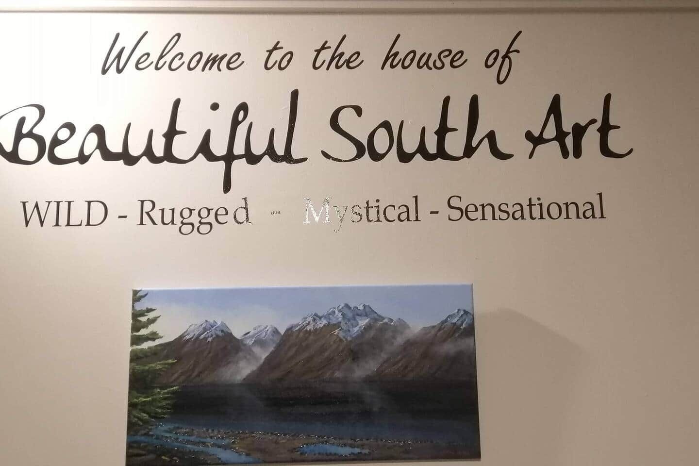 A wall with a sign that reads 'Welcome to the house of Beautiful South Art' and lists 'WILD - Rugged - Mystical - Sensational' as art styles.