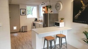 Una cocina compacta con una isla central, electrodomésticos de acero inoxidable y un reloj en la pared.