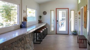 Une cuisine dotée d’un plan de travail en pierre, de tabourets de bar et offrant une vue sur l’extérieur.